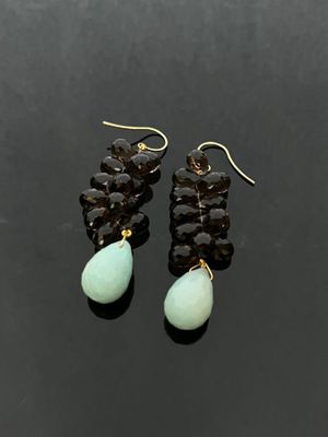 a pair of earrings with black and green beads on a black surface