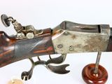 an old gun with a wooden handle and a wooden stand