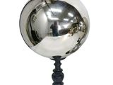 une boule argentée posée sur un socle noir, sur un fond blanc