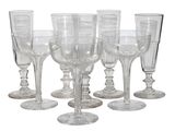 six verres à vin transparents posés les uns à côté des autres sur une surface blanche