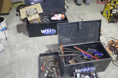une boîte à outils noire contenant des outils, dans un garage