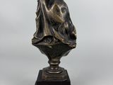 a bronze statue of a woman holding a flag on top of a pedestal
