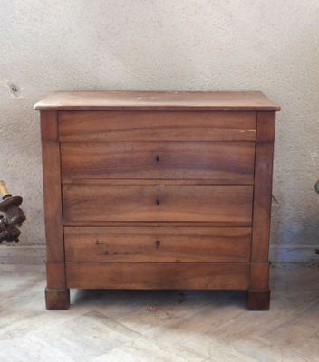 a small wooden chest of drawers next to a chair