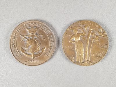 deux pièces d'or posées sur une surface blanche : l'une représente une femme et l'autre un homme
