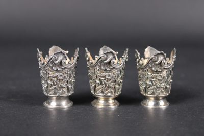 trois vases en argent posés les uns à côté des autres sur une table