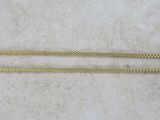 a close up of two gold chains on a white surface