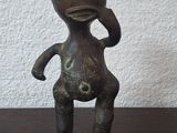 une petite statue représentant une personne, posée sur une table en bois