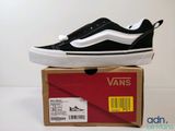une boîte sur laquelle est posée une paire de chaussures noires et blanches