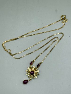 a close up of a necklace with a flower design on it