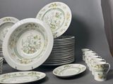 many plates and cups on a table with a curtain in the background
