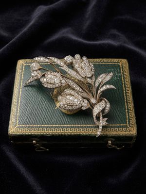 a gold and diamond broochle on a black velvet background