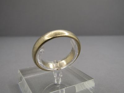 une bague en or posée sur un socle transparent