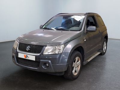 un SUV Suzuki gris garé dans une pièce au sol noir