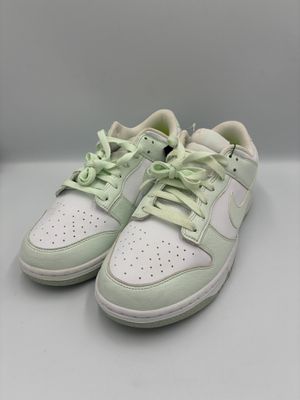a pair of white sneakers with green laces on them
