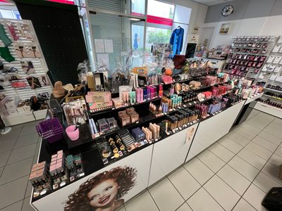 un présentoir de produits cosmétiques dans un magasin, avec le visage d'une femme peint sur le mur