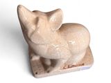une petite figurine représentant un chat posée sur une surface blanche