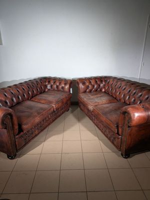 pair of leather chesterfield sofas in a room with tile flooring
