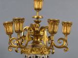 a gold and white vase with five candles on it