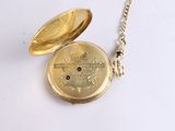 a gold pocket watch on a chain on a white surface