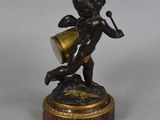 bronze figurine of a cupid playing a musical instrument on a marble base
