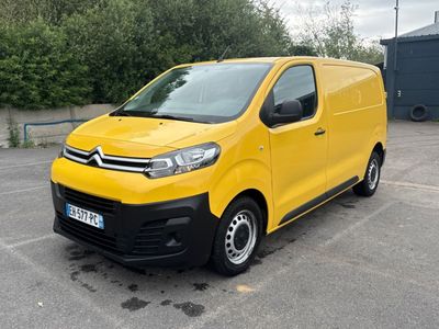 La camionnette jaune est garée sur un parking, avec des arbres en arrière-plan.
