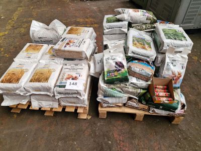 many bags of food sitting on pallets on the ground
