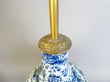 a blue and white vase with a gold top on a table