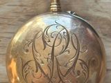 a gold pocket watch with a monogram on it