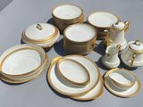 a lot of white and gold plates and cups on the table