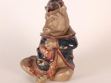 a ceramic statue of a bear sitting on a stool
