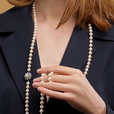 gros plan sur une femme portant un collier de perles muni d'un fermoir en diamant