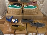 plusieurs paires de chaussures posées sur des cartons, sur un plancher en bois