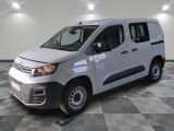 La camionnette blanche est garée dans le garage, sur un sol à carreaux.