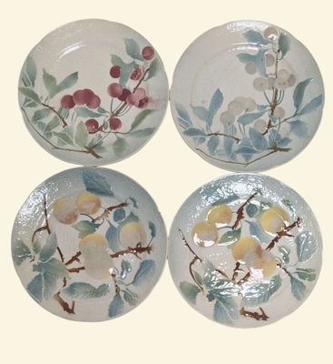 quatre assiettes ornées de fleurs et de feuilles peintes sur fond blanc