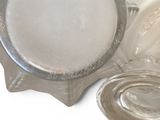 a glass bowl with a lid sitting on a table next to a plate