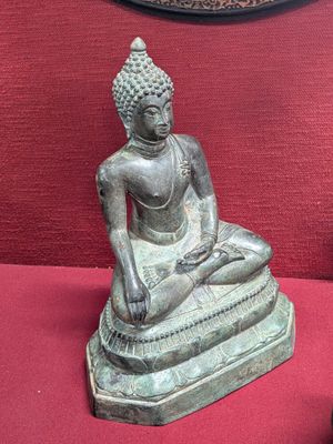 a statue of a buddha sitting on a red surface