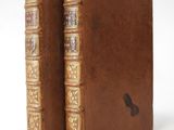 an old book with a brown cover sitting on top of a white table
