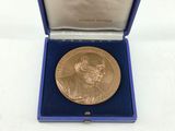 a gold medal in a blue box on a white surface