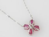 a close up of a silver necklace with a pink flower on it