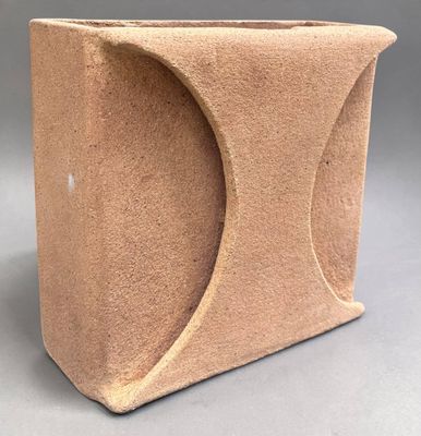 a brown vase that has a curved design on it