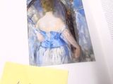 un livre ouvert sur lequel figure l'image d'une femme en robe bleue