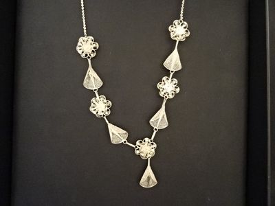 Un collier en argent est présenté dans un écrin noir