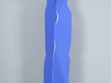 sculpture bleue représentant une femme debout sur un plancher en bois, devant un mur bleu