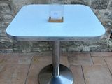 a small table with a sign on it on a brick floor