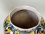 a yellow and blue vase sitting on a white table