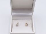 une paire de boucles d'oreilles dans un écrin posé sur une surface blanche