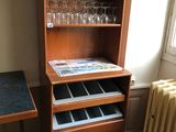 une armoire en bois sur laquelle sont posés des verres à vin et une table au plateau noir