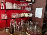 bottles and glasses on a shelf in a room with a red wall