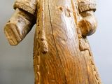 une statue en bois représentant un homme portant un chapeau et un manteau