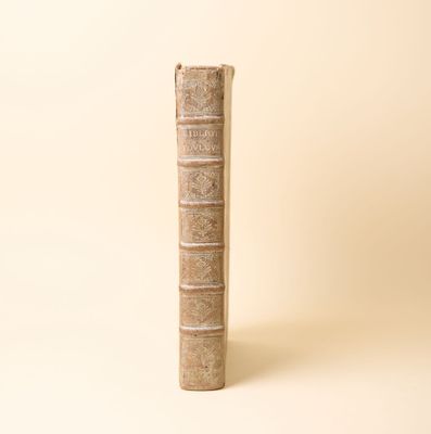 un vieux livre posé sur une table à côté d'un mur blanc